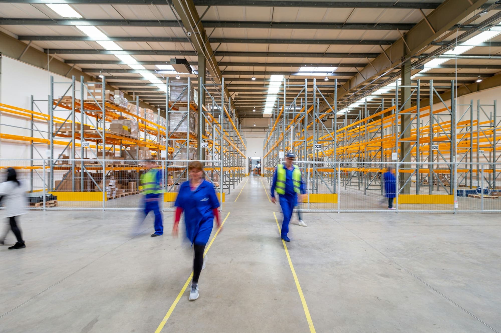 Warehouse staff walking along a racked aisle inside a distribution centre